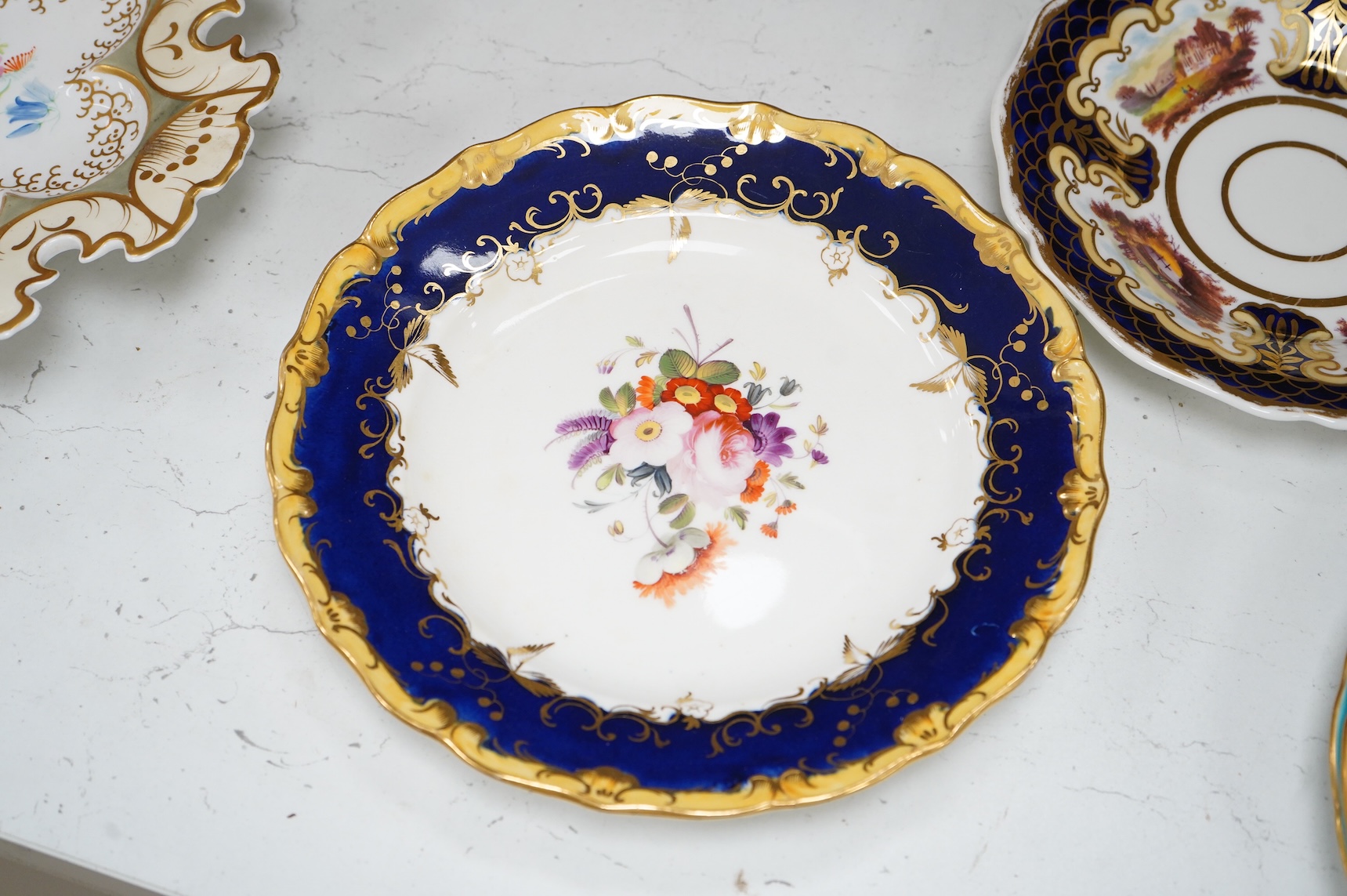 A collection of 19th century English dessert wares to include a pair of Flight, Barr and Barr ‘fantastic birds’ green ground dessert plates, various Ridgway dessert plates, five Minton botanical plates with tooled gilt b